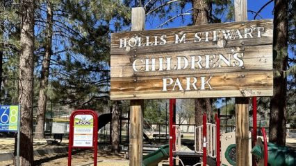 Signpost in front of park that reads "Hollis M. Stewart Children's Park"