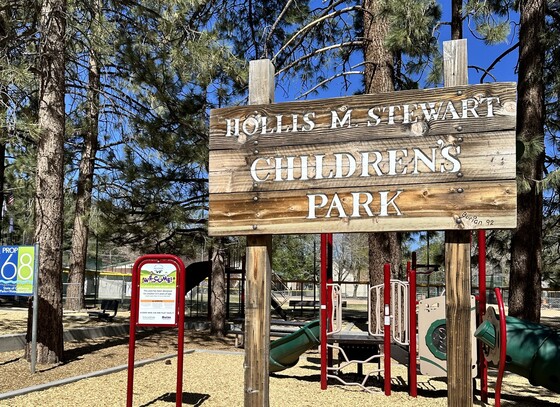 Signpost in front of park that reads "Hollis M. Stewart Children's Park"