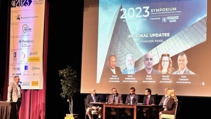 Presenters sitting at a table on a stage at the Symposium