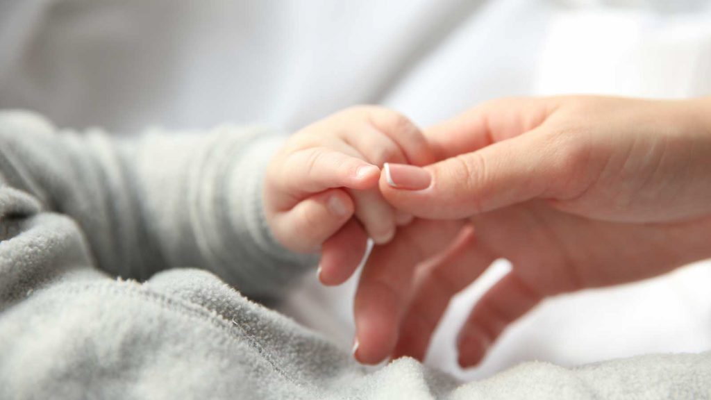 Adult hand holding a babies hand