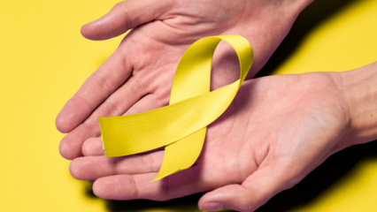 Two hands holding a yellow ribbon