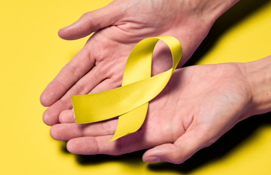 Two hands holding a yellow ribbon