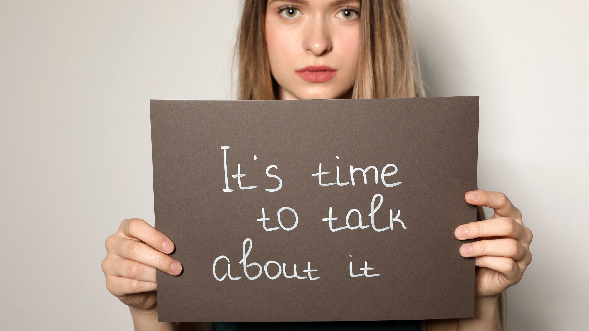 Photo of woman holding sign that says It's Time to Talk About It.