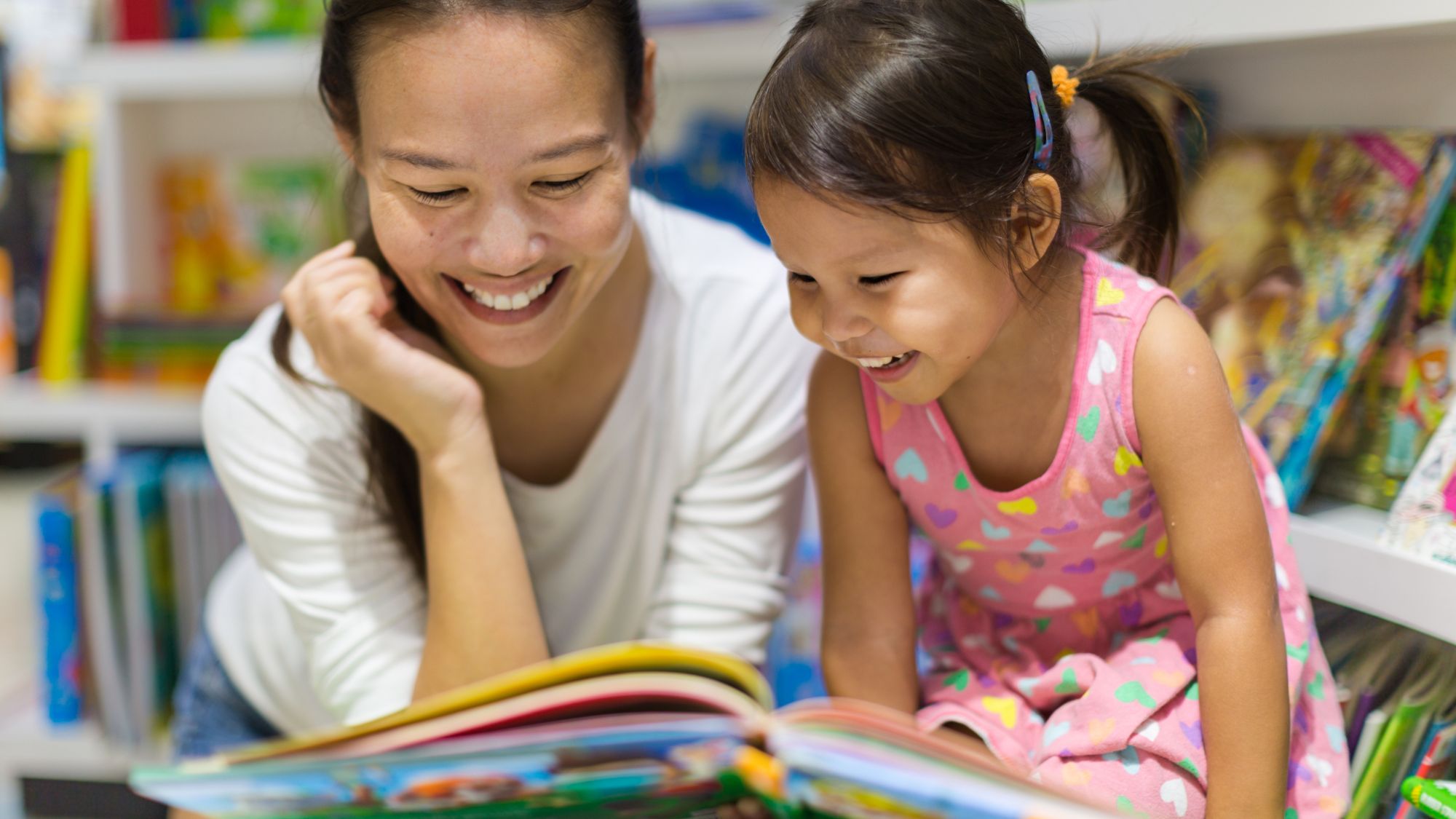 Photo of mom and daughter reading a book.