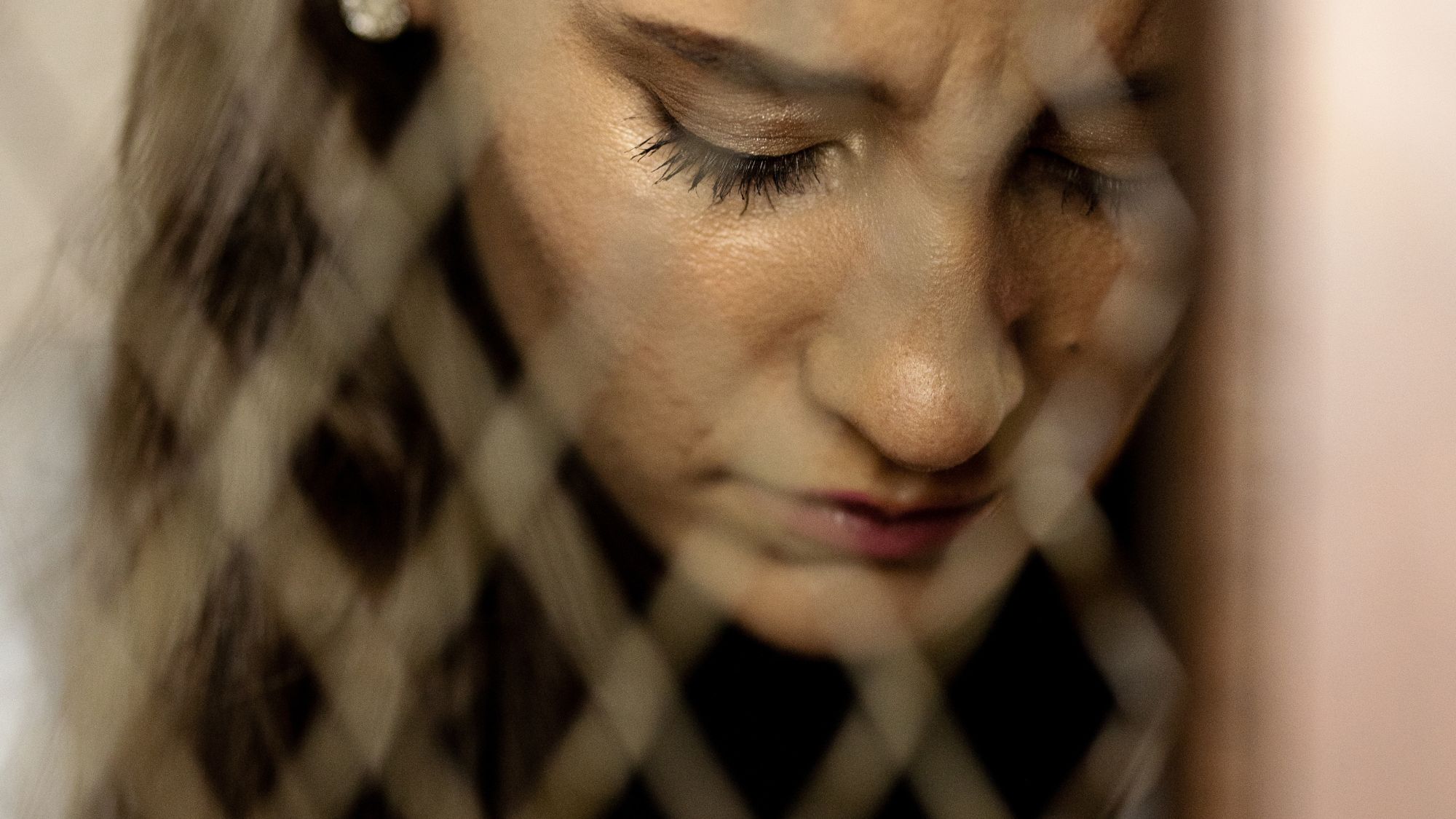 Photo of woman looking down behind a fence with eyes closed.