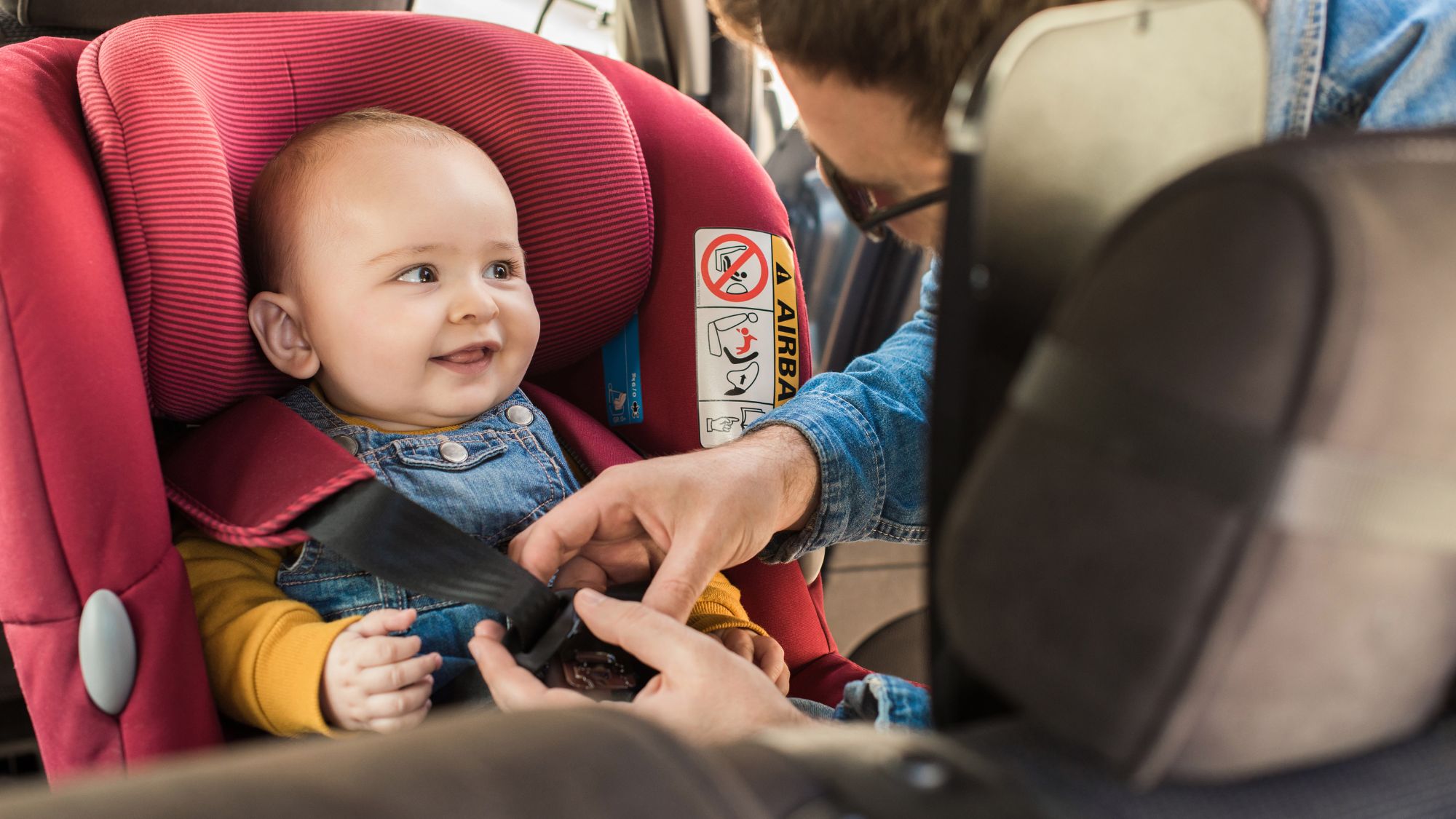 Photo of child being secured into a car seat.