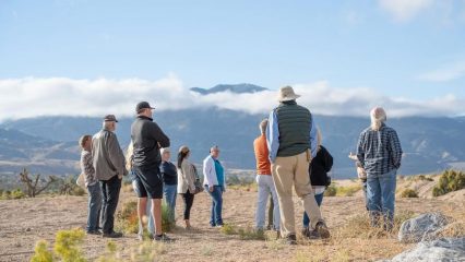 Group of people in desert with mountains in background.