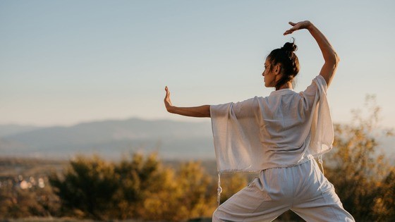 Woman performing Tai Chi in a white outfit.