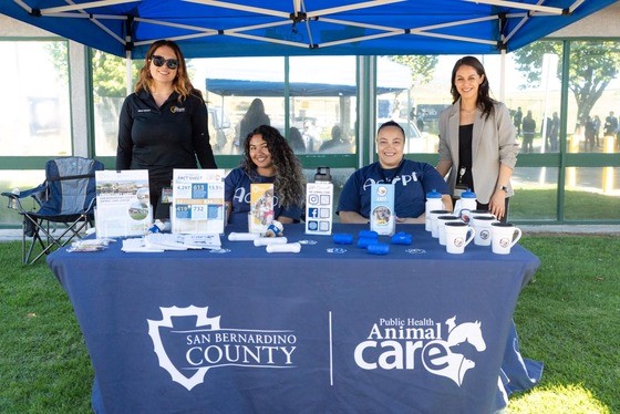 Four employees of San Bernardino County Animal Care with pamphlets at a table.