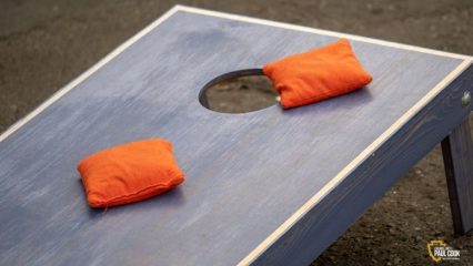 Cornhole board with two orange bags