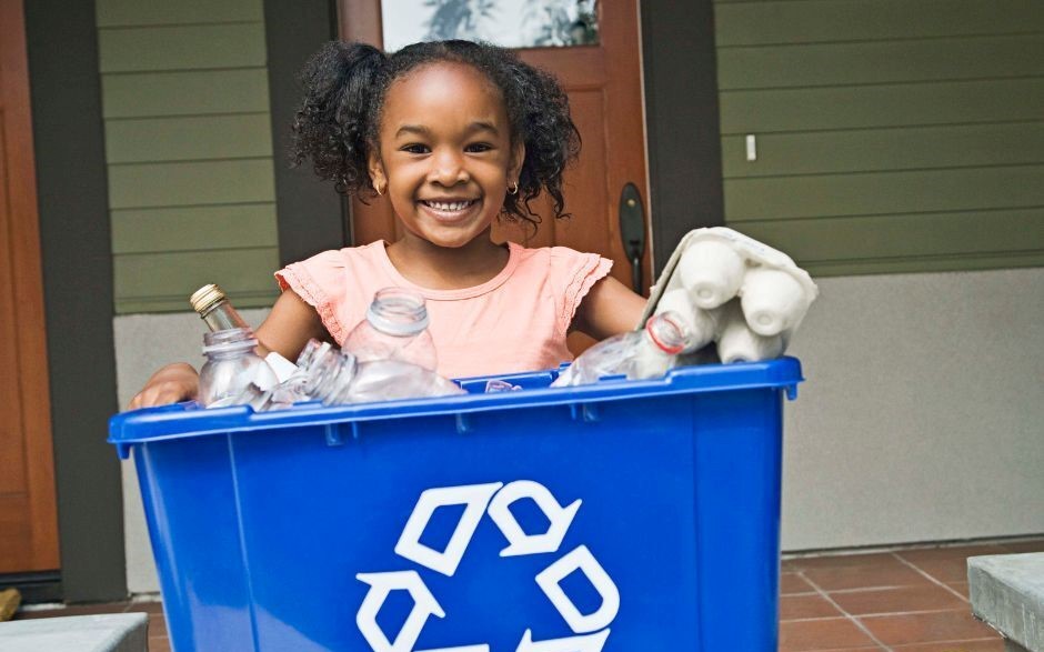 Young girl holding recycling bin