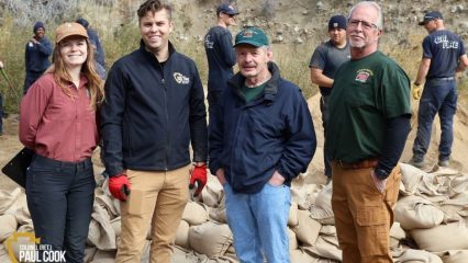 Photo of four people in front of sandbags