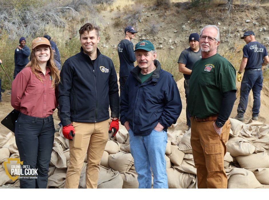 Photo of four people in front of sandbags