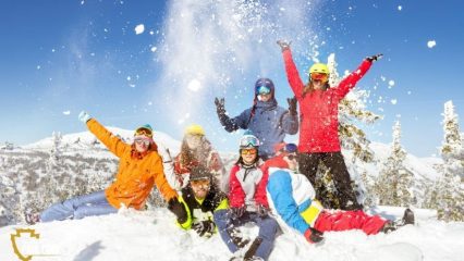 People playing in the snow with colorful suits on.