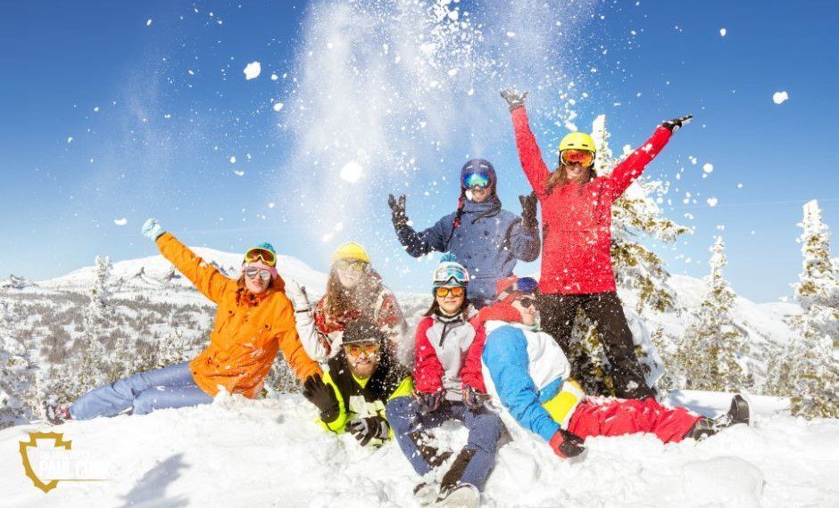 People playing in the snow with colorful suits on.