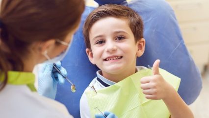 boy at the dentist giving thumbs up