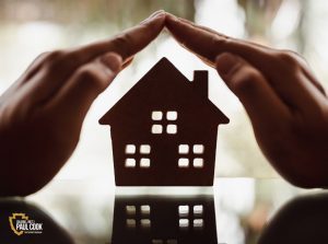 Person holding hands over a wooden house