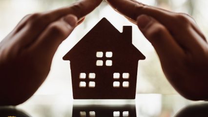 Person holding hands over a wooden house